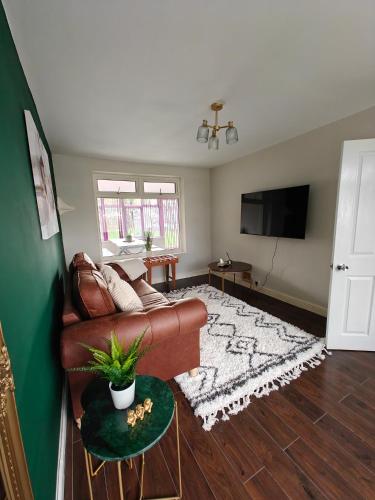 a living room with a couch and a television at Under 10 Mins to NEC BHX - Walk to JLR -2 Large Living Areas - 4 Bedroom Spacious Home - Van Parking x2 - 5 Beds Excellent Equipped Home - NR A45 Solihull Bypass M42 HS2 Works in Solihull