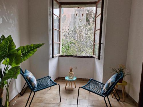 - deux chaises et une table dans une chambre avec fenêtre dans l'établissement Appartement centre Saint Florent, à Saint-Florent