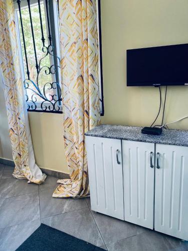 a living room with a flat screen tv and a window at Homeaway4m home in Dar es Salaam