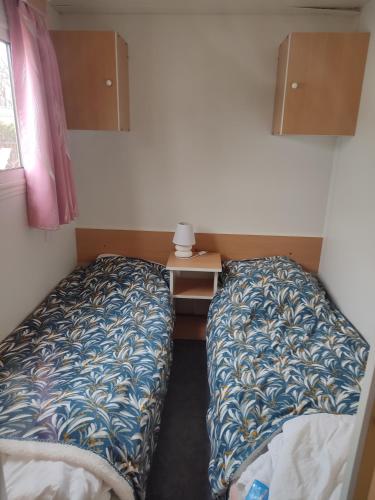 Cette petite chambre comprend deux lits et un bureau. dans l'établissement Mobil home a ste croix du verdon camping 3, à Sainte-Croix-de-Verdon