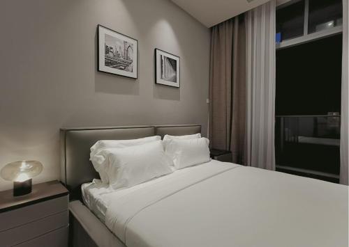 una camera da letto con letto, lenzuola e cuscini bianchi di Royce Residence Kuala Lumpur by Collective Haus a Kuala Lumpur