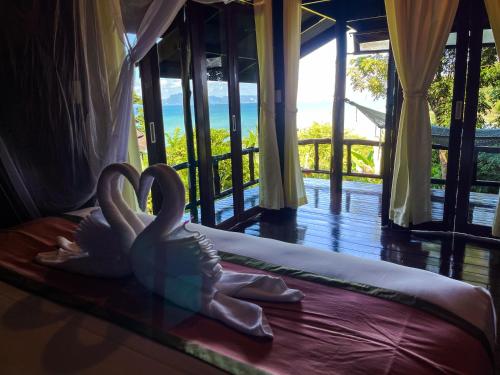 two swans sitting on a bed in a room at Hillhouse - Koh Yao Noi in Ko Yao Noi