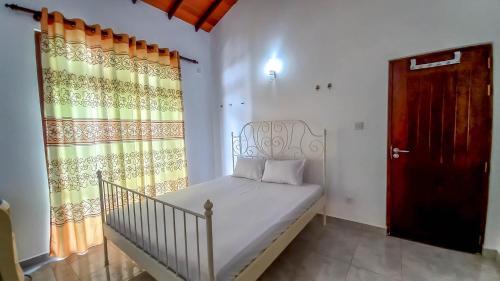 a small bedroom with a bed and a red door at Newolivevilla in Katunayake
