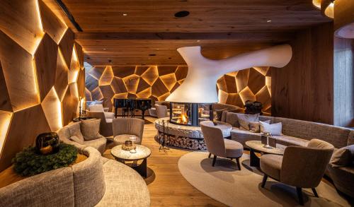 a lobby with couches and chairs and a fireplace at Savoy Dolomites Luxury & Spa Hotel in Selva di Val Gardena