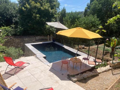 - une piscine avec une table, un parasol et des chaises dans l'établissement La Villa Tranquille aux portes des Cévennes, à Brissac