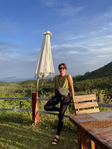 a woman sitting on a bench next to an umbrella at Hillhouse - Koh Yao Noi in Ko Yao Noi