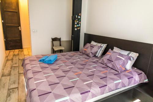 a bed with a purple comforter and pillows at Loft Style Apartment in Tbilisi City