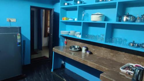 a blue kitchen with a counter with blue shelves at Noble Homestay in Munnar