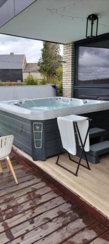 a hot tub sitting on a deck with two chairs at Trees Fontain in Jalhay