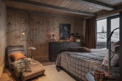 a bedroom with wooden walls and a bed and a chair at Hyttekos Lodge: luxury ski-in/ski-out chalet in Kvitfjell