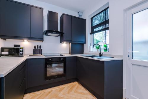 a kitchen with black cabinets and a window at 4 Bedroom House Eccles in Manchester