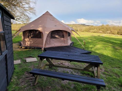 a tent with a picnic table in a field at Hideaway Escapes Rental Tents, 4 Unique tents NO BEDDING SUPPLIED in Narberth