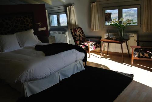 a bedroom with a bed and a living room at Hotel Rural El Algaire in Arquera de Salas