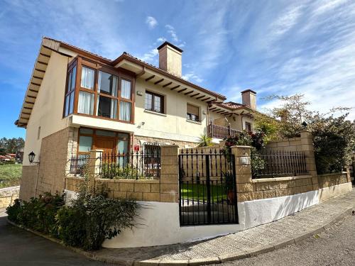 una casa con una valla delante de ella en "LAS CAMELIAS SOMO" un lugar para desconectar!! Vistas al MAR!! en Somo