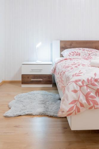 a bedroom with a bed with a nightstand and a rug at Apartma Lozar in Ajdovščina