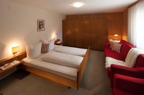 ein Schlafzimmer mit einem Bett und einem roten Sofa in der Unterkunft Gästehaus Lässer in Mellau