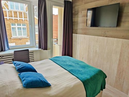 Schlafzimmer mit einem Bett und einem TV an der Wand in der Unterkunft Hotel Sfinx in De Panne