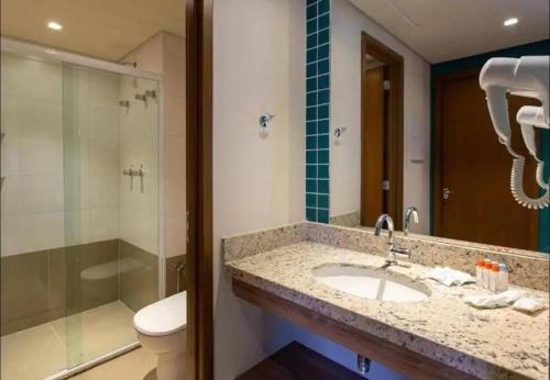 une salle de bain avec un lavabo, une douche et des toilettes dans l'établissement Apto em resort Solar das Águas, à Olímpia