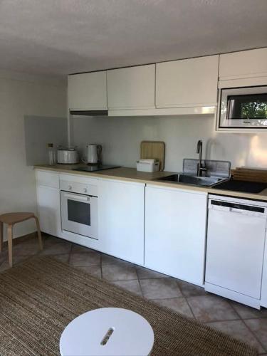 une cuisine avec des armoires blanches et une table à l'intérieur dans l'établissement T2 - Rez de Jardin, proche de la mer, à Carqueiranne