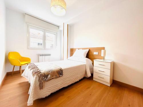 1 dormitorio con 1 cama y 1 silla amarilla en Apartamento San José, en Milladoiro