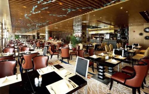 a dining room with tables and chairs in a restaurant at JingLai Bushe Hotel Bund Nanjing West Road Shanghai in Shanghai
