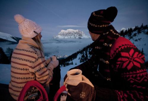 a man and woman sitting on top of a snow covered mountain at Chalet Melodie in Ehrwald