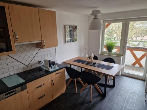 cocina con mesa, sillas y ventana en Ferienwohnung Forchtenberg 3 Zimmer, en Forchtenberg