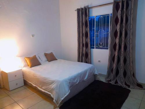 a small bedroom with a bed and a window at Katembe Beach Paradise in Maputo
