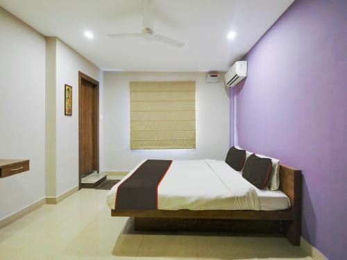 a bedroom with a bed and a purple wall at Collection O Nirvana Lodge in Guwahati