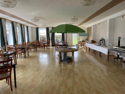 a room with tables and chairs and a green umbrella at Harzhotel Grünett in Langelsheim