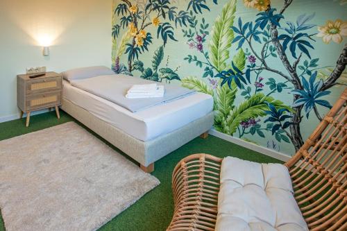 1 dormitorio con 1 cama y 1 silla de mimbre en WannerHus Hotel, en Grömitz