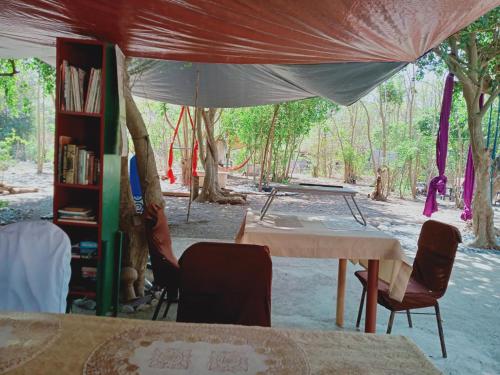a tent with a table and chairs and a book shelf at SECLUDED GLAMPING YOGA SAMADHI fan 2 kubos 8 pax in Rimus