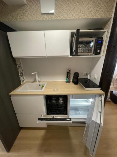 une petite cuisine avec un évier et un micro-ondes dans l'établissement Bmco cottage, à Estrées-Saint-Denis
