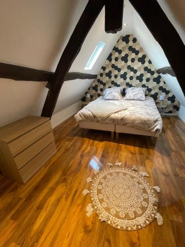 a bedroom with a bed and a rug on a wooden floor at Bmco cottage in Estrées-Saint-Denis