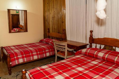 a hotel room with two beds and a table and a table at Roxy's Mountain Lodge in Roseau