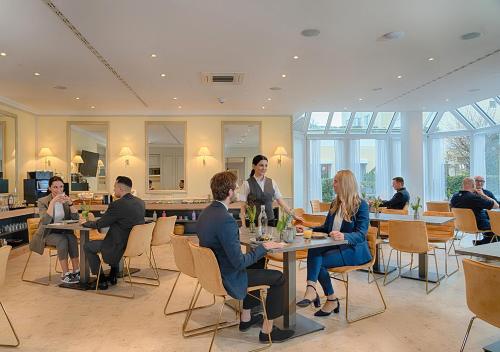 a group of people sitting at tables in a restaurant at Hotel Am Brinkerplatz in Essen