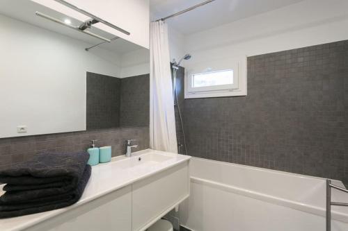 une salle de bain avec un lavabo, une baignoire et un miroir dans l'établissement Joli Duplex rénové à neuf de 72m², à Fresnes