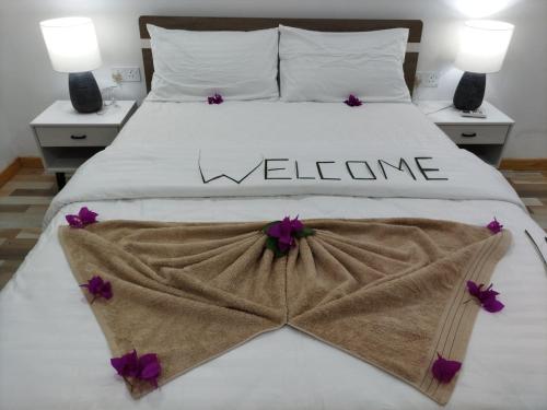 Una cama blanca con un cartel de bienvenida. en The Happiness Sun Suites, en Fodhdhoo