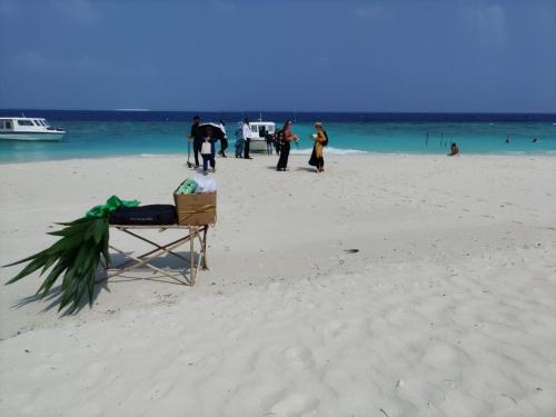 a chair on a beach with people in the water at The Happiness Sun Suites in Fodhdhoo