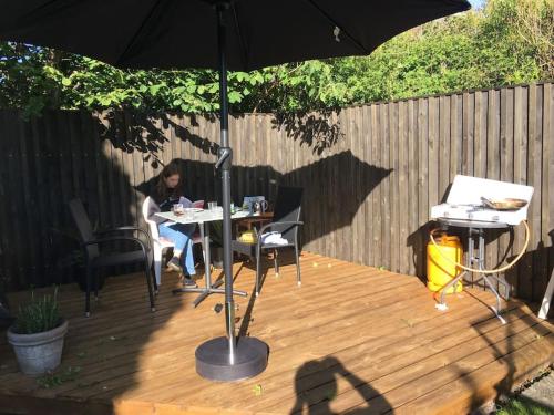 a woman sitting at a table under an umbrella at Nyd den skønne natur ved hav og fjord in Thyborøn
