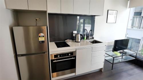 una cocina con nevera de acero inoxidable y armarios blancos en Sky Stars Essential Home, en Auckland