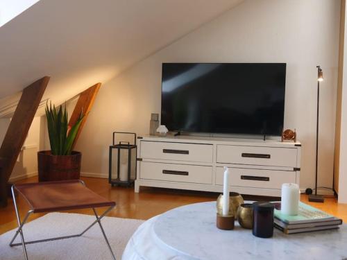 a living room with a large television on a white dresser at Spacious Penthouse close to center in Stockholm