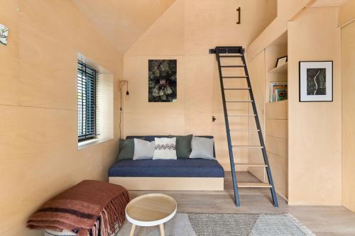 Habitación pequeña con cama y escalera en Hello Zeeland - Tiny Houses Groede en Groede