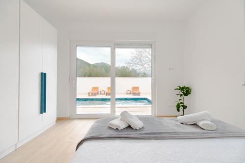 ein weißes Schlafzimmer mit einem großen Bett mit zwei Kissen in der Unterkunft House Bartulovic - Jan Apartment with a pool in Ston