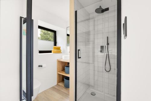 een badkamer met een douche en een glazen deur bij Hello Zeeland - Tiny Houses Groede in Groede