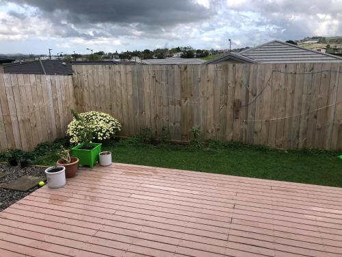 una terraza de madera con macetas y una valla de madera en Stand alone house - Pukekohe, en Helvetia