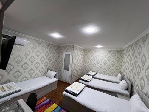 Habitación con 3 camas y TV. en Aziz Hotel, en Samarkand