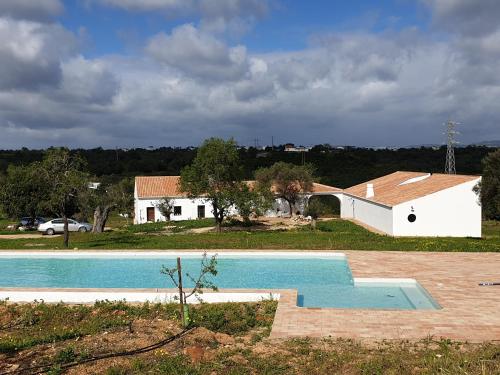 une maison avec une piscine en face d'un bâtiment dans l'établissement Monte das Açoteias - Agroturismo, à Tavira