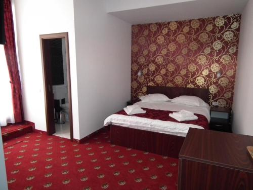 a hotel room with a bed and a red carpet at Vila Queen Mary in Constanţa