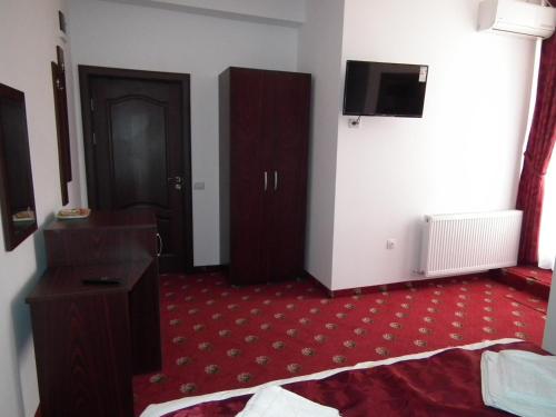 コンスタンツァにあるVila Queen Maryのベッド1台、壁掛けテレビが備わるホテルルームです。